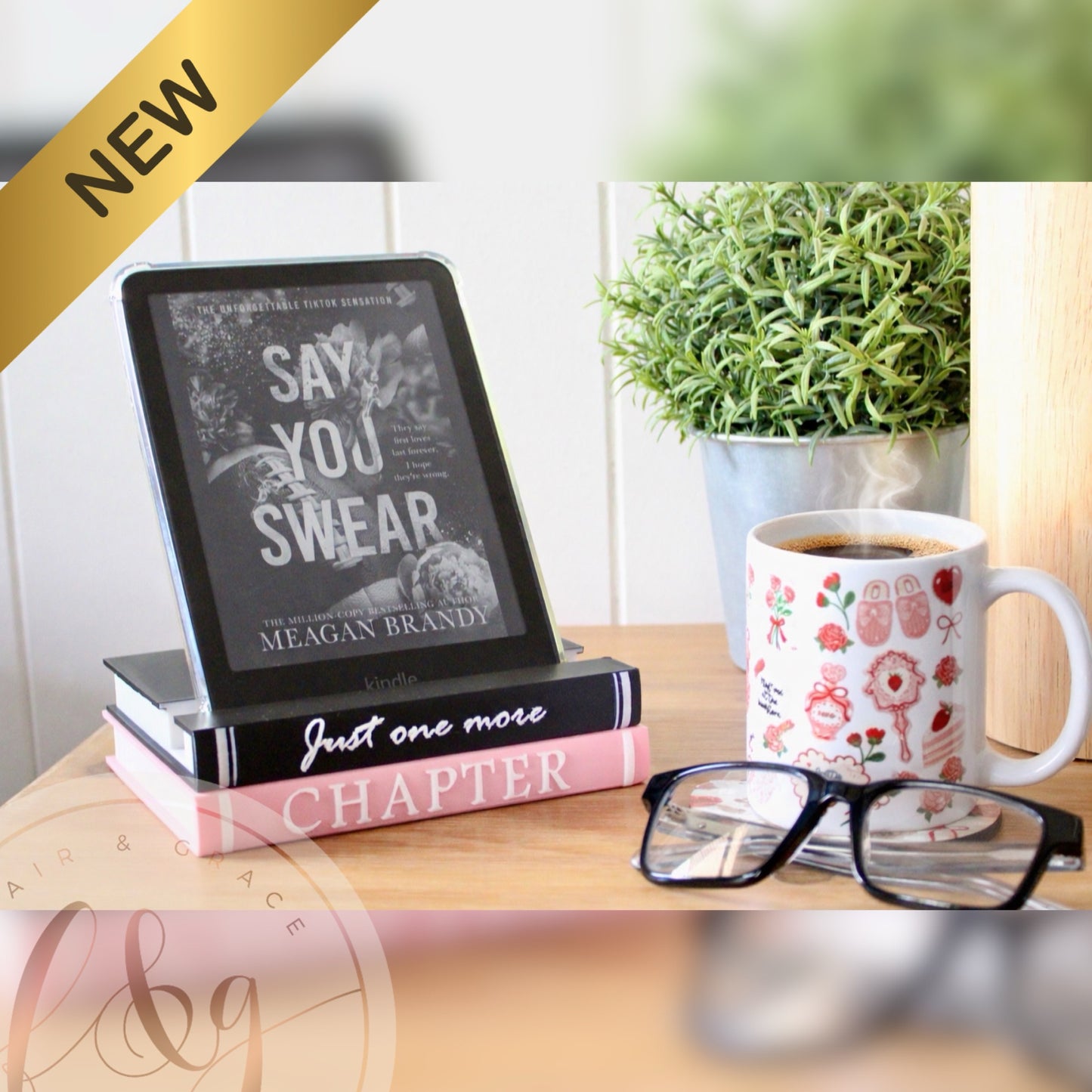 E-reader on books with a mug and glasses on a wooden surface